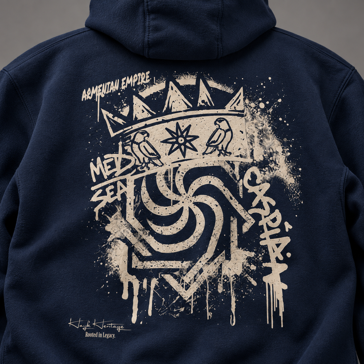Close-up of the back of a navy hoodie with a large distressed cream graphic print featuring birds, a crown, paint splatter, and stylized text including 'Armenian EMPIRE' and 'MED SEA'.